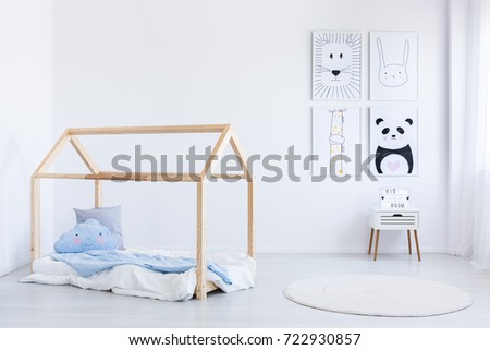 Scandinavian style boy's bedroom with blue pillow and coverlet on handmade bed and posters on wall