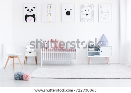 Girl's bedroom with pastel pompons on floor and pink pillows on bed against wall with drawings