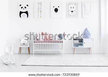 Girl's bedroom with rocking horse and bed with pink pillows against wall with animal posters gallery