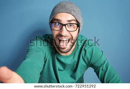 Young man taking selfie against color wall background