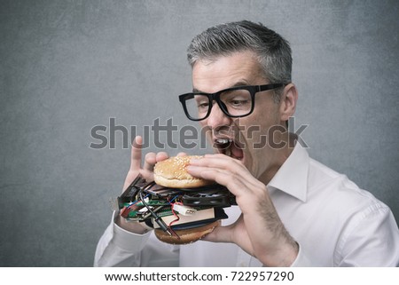 Greedy nerd IT technology enthusiast eating a sandwich filled with hardware and computer parts Royalty-Free Stock Photo #722957290