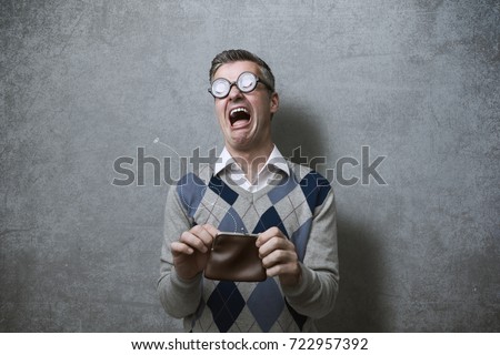 Broke man with thick glasses holding an empty purse and crying, poverty and debts concept Royalty-Free Stock Photo #722957392