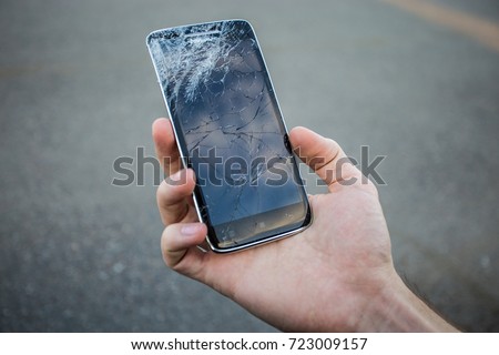 Men's hands hold a smart phone with a cracked screen