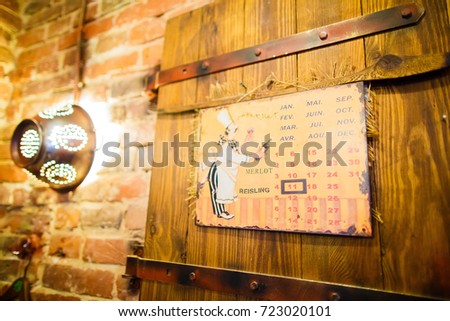 The side portrait of the calender with the cooker placed on the wooden antique door in the cafe with the brick walls decorated with shining colander.