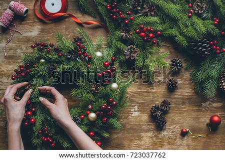 top view of florist hands making Christmas wreath on wooden tabletop Royalty-Free Stock Photo #723037762