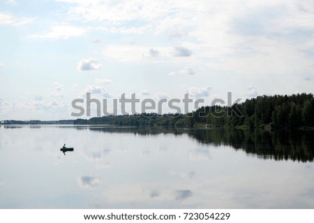 A lone fisherman on the mirrored surface of the pond, Latvia