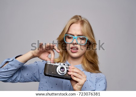 young woman in glasses adjusts the camera on a gray background                               