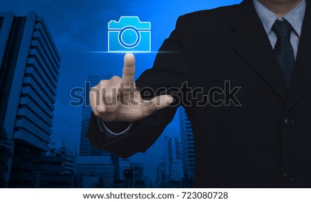 Businessman pressing camera flat icon over modern office city tower, Business camera service concept