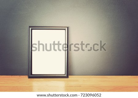 Photo frame on wooden table and cement wall background