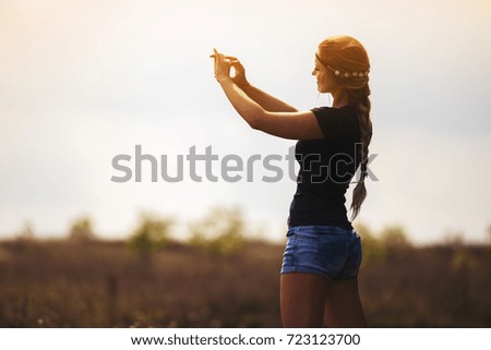 Hippie girl taking picture using smartphone outdoors