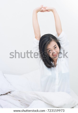 Pretty asian woman stretching in bed after wake up 
