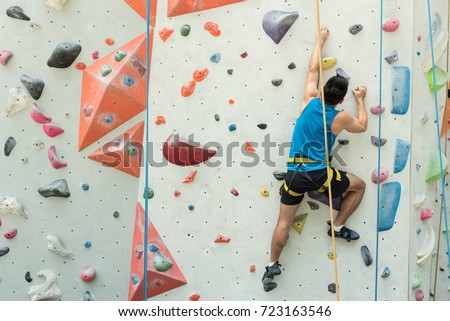 Fit asian man rock climbing indoors at the gym Royalty-Free Stock Photo #723163546