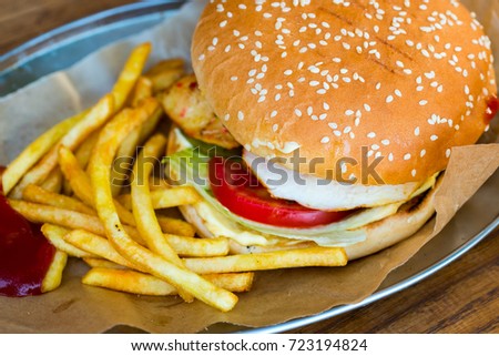 hamburger bun with sesame and chicken fillet with salad and fried potatoes