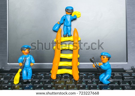 Computer repair concept, plasticine workers cleaning and repairing a laptop. 
