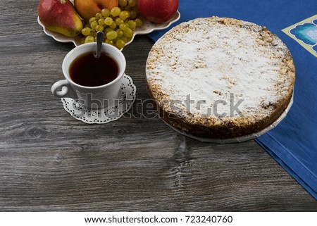 Thanksgiving Dessert. Homemade berry cake, cup of tea and fresh juicy fruits, peach, apple, pear and grapes on wooden table background.