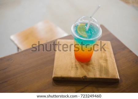 Three color drink in one glass on the table and one chair