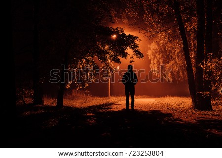 silhouette of a man in an autumn foggy night park.