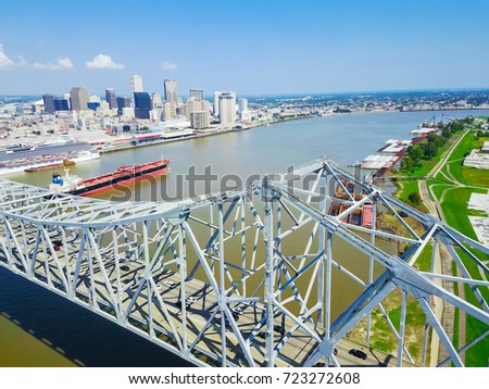 Aerial view of Crescent City Connection and riverside Downtown New Orleans again cloud blue sky. Overhead view the cantilever bridges, cruise ship, cargo ship, container terminal on Mississippi river.