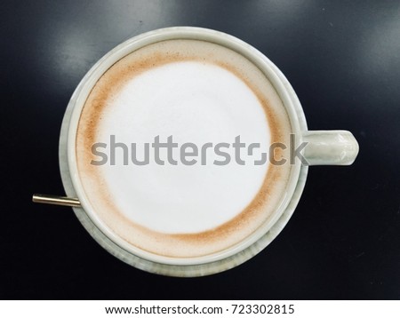 A cup of coffee with heart pattern in a white cup on wooden background Vintage