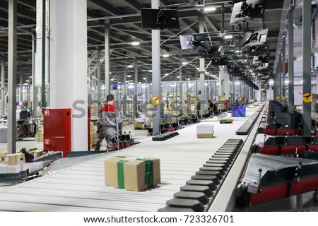 People work in modern workshop with conveyor, many displays in warehouse Royalty-Free Stock Photo #723326701