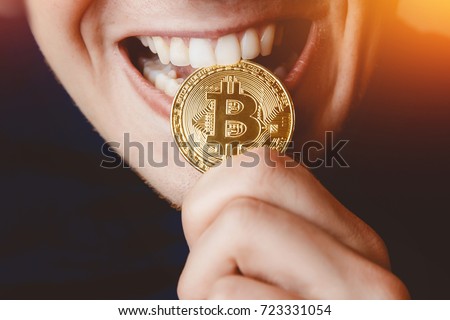 Bitcoin. Man bites a gold coin with his teeth Royalty-Free Stock Photo #723331054