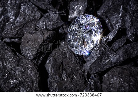 A single solitaire Diamond in amongst some pieces of coal.  Royalty-Free Stock Photo #723338467
