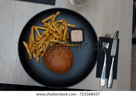 Hamburger served with French fries and sauce. Top view.