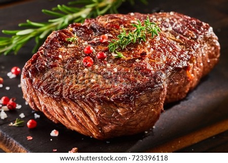Piece of roast beef with spices served on wooden cutting board Royalty-Free Stock Photo #723396118