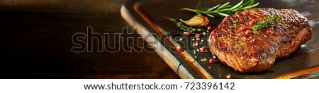 Piece of cooked rump steak with spices served on wooden cutting board Royalty-Free Stock Photo #723396142