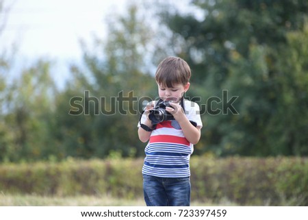 Four years old boy taking photos with camera. Little photographer with professional dslr camera