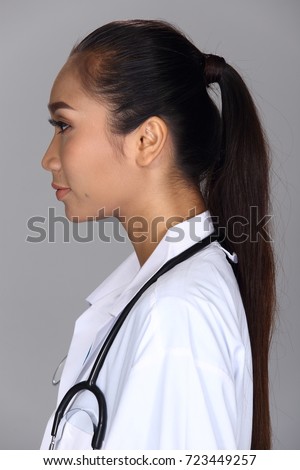 Asian Woman after applying make up black hair style. no retouch, fresh face with acne, mole, nice and smooth skin. Studio lighting grey background, doctor look with stethoscope, rear side back view