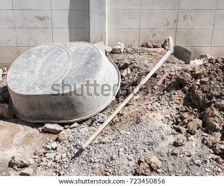 Large plastic bucket and metal hoe near the house wall for counstruction the modern house.