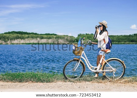woman photographer taking photo for view of mangrove forest by camera.Asian lady tourist riding a bicycle and looking for view of nature on holiday. 