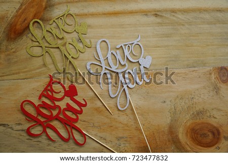 Top or flat lay view of Photo booth props a Red, Silver and Gold text Love You on a wooden background flat lay. Birthday parties and weddings.   