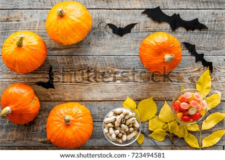 Halloween background. Pumpkins, paper bats and autumn leaves on wooden background top view copyspace