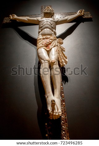 Wooden statue of Jesus Christ nailed to the cross in front of black background