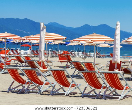 Summer beach of Italy, Ligurian coast of Italy in province of La Spezia. Red sun umbrellas and red beds. Beach resort.