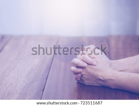 Woman hands praying  on wooden table with the light from above with copy space fro your text.