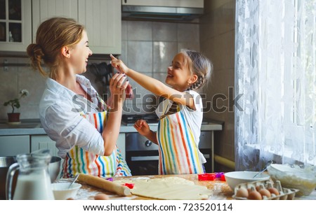 Happy family mother and child daughter bake kneading dough in the kitchen