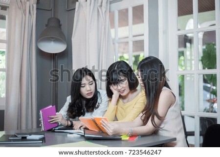 Young asian girl student discussing things and working with laptop or notebook on a project while sitting in the coffee shop
