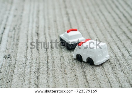 transportation concept - cute police car and ambulance van toy model on concrete road