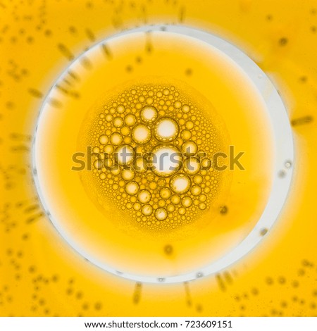 Detail of oil bubbles formed at the surface of water with predominant yellow