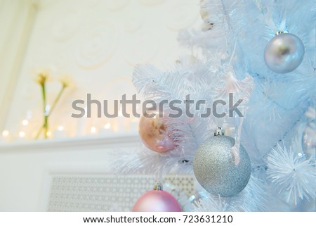A close picture of silver and pink decorations on a white new year tree. Place setting for Christmas in white with white Christmas tree.