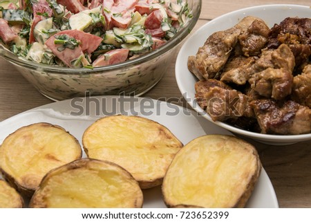 Baked potatoes on a plate and fried meat and salad.