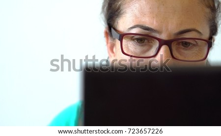 Sad and tired woman working beside table, looking on laptop