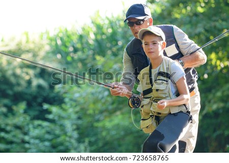 Father teaching son how to fly-fish in river Royalty-Free Stock Photo #723658765