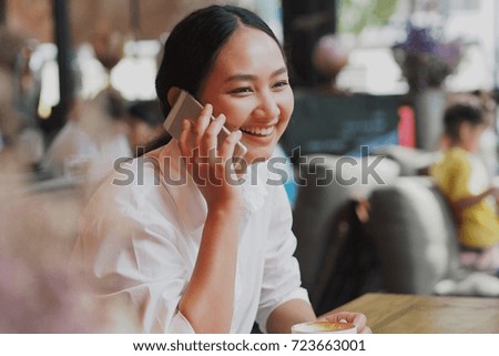 Beautiful Asian woman drinking coffee and working with laptop in coffee shop.