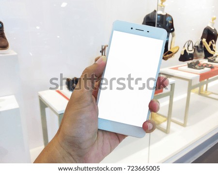 Close up of white mobile phone in hand with shop in shaping mall,this image for business concept.