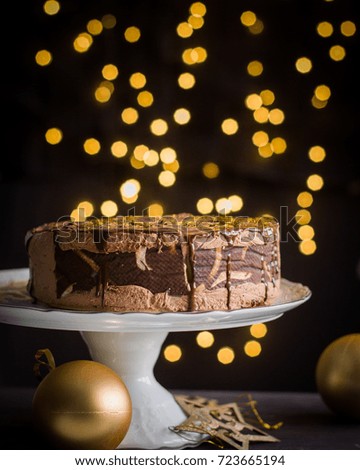 Chocolate mousse cake decorated with burning fireworks. Background of Christmas lights. Atmospheric festive card
