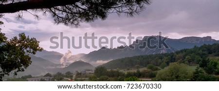 Misy landscape fog in Pyrenees mountains. Factory in middle, industrial scenery